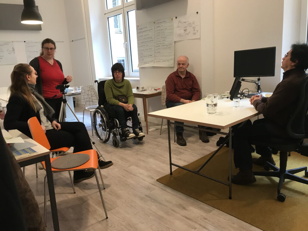 Einige Menschen sitzen in einem Büro kreisförmig zusammen.